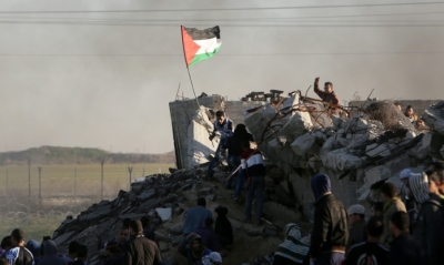 Manifestante palestino segura bandeira durante confrontos com for&ccedil;as israelenses em Gaza