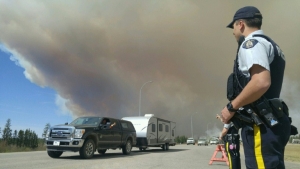 Um policial auxilia ve&iacute;culos na sa&iacute;da da cidade de Fort McMurray, Canad&aacute;, no dia 6 de maio de 2016