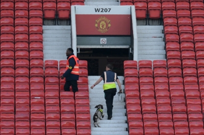 Um c&atilde;o farejador e membros dos servi&ccedil;os de seguran&ccedil;a fazem buscas na arquibancada do est&aacute;dio Old Trafford, em Manchester, no dia 15 de maio de 2016