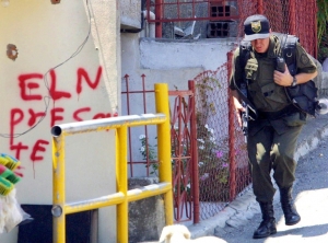 Um policial passa em frente a uma picha&ccedil;&atilde;o da guerrilha ELN, em Medell&iacute;n, Col&ocirc;mbia, no dia 14 de outubro de 2002