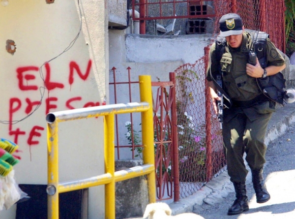 Um policial passa em frente a uma picha&ccedil;&atilde;o da guerrilha ELN, em Medell&iacute;n, Col&ocirc;mbia, no dia 14 de outubro de 2002