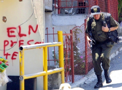 Um policial passa em frente a uma picha&ccedil;&atilde;o da guerrilha ELN, em Medell&iacute;n, Col&ocirc;mbia, no dia 14 de outubro de 2002