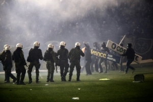 Panathinaikos' fans clash with riots police after the cancellation of the Greek Super League match between Panathinaikos and Olympiakos at Apostolos Nikolaides stadium in Athens on November 21, 2015. Referee Andreas Pappas made the decision 30 minutes after the Super League match was due to start after taking into account the violence both inside and outside the Apostolos Nikolaidis Stadium. Immediately after the decision was announced to the spectators, dozens of fans rushed onto the pitch and fought with riot-trained police. AFP PHOTO / SOOC / Alexandros Michailidis