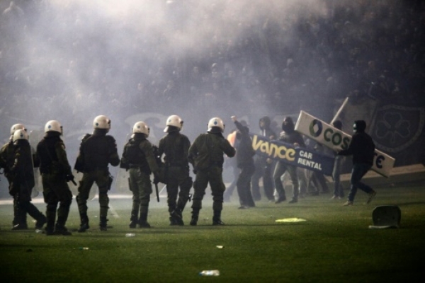 Panathinaikos' fans clash with riots police after the cancellation of the Greek Super League match between Panathinaikos and Olympiakos at Apostolos Nikolaides stadium in Athens on November 21, 2015. Referee Andreas Pappas made the decision 30 minutes after the Super League match was due to start after taking into account the violence both inside and outside the Apostolos Nikolaidis Stadium. Immediately after the decision was announced to the spectators, dozens of fans rushed onto the pitch and fought with riot-trained police. AFP PHOTO / SOOC / Alexandros Michailidis