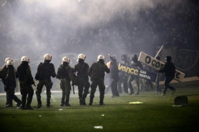 Panathinaikos' fans clash with riots police after the cancellation of the Greek Super League match between Panathinaikos and Olympiakos at Apostolos Nikolaides stadium in Athens on November 21, 2015. Referee Andreas Pappas made the decision 30 minutes after the Super League match was due to start after taking into account the violence both inside and outside the Apostolos Nikolaidis Stadium. Immediately after the decision was announced to the spectators, dozens of fans rushed onto the pitch and fought with riot-trained police. AFP PHOTO / SOOC / Alexandros Michailidis