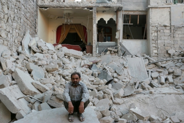 (Arquivo) Um homem s&iacute;rio &eacute; visto sentado em frente &agrave;s ru&iacute;nas do pr&eacute;dio em que morava ap&oacute;s bombardeios no norte de Aleppo, em 13 de junho de 2014