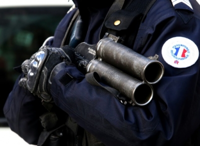 A French police officer holds a "flash-ball" gun, used to launch plastic bullets in riot situation, stands next to the courthouse of Reims, on February 15, 2016, as supporters involved in clashes with riot police following a French L1 football match where a Bastia's supporter was seriously injured, arrive for immediate trial.