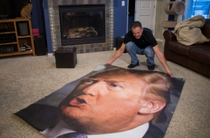 Partid&aacute;rio de Donald Trump estende um banner com a imagem do pr&eacute;-candidato republicano na sala de sua casa, em Iowa