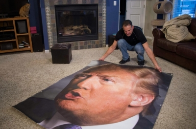 Partid&aacute;rio de Donald Trump estende um banner com a imagem do pr&eacute;-candidato republicano na sala de sua casa, em Iowa