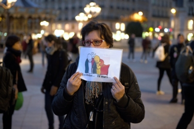 Mulher segura charge feita pelo cartunista franc&ecirc;s Plantu mostrando a bandeira da Fran&ccedil;a consolando a bandeira belga, em frente &agrave; prefeitura de Paris, em 22 de mar&ccedil;o de 2016