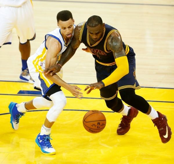 Curry (E) disputa a bola com Lebron James na primeira partida da final da NBA, em 2 de janeiro, em Oakland