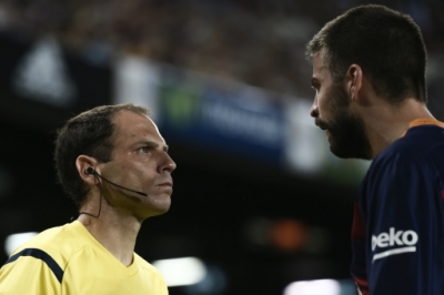 An assistant referee looks at Barcelona's defender Gerard Pique (R) during the Spanish Supercup second-leg football match FC Barcelona vs Athletic club Bilbao at the Camp Nou stadium in Barcelona on August 17, 2015. AFP PHOTO / JOSEP LAGO