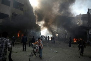 Moradores observam &aacute;rea atingida por bombardeio atribu&iacute;do ao regime s&iacute;rio na cidade rebelde de Duma, ao leste da capital Damasco