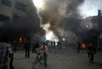 Moradores observam &aacute;rea atingida por bombardeio atribu&iacute;do ao regime s&iacute;rio na cidade rebelde de Duma, ao leste da capital Damasco
