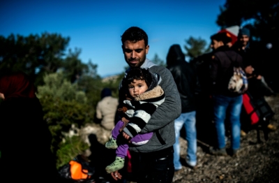 Pai s&iacute;rio detido por soldados turcos carrega filho em Dikili, oeste da Turquia, em 5 de mar&ccedil;o de 2016