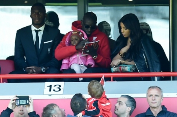 Liverpool's French defender Mamadou Sakho (top C) signs a programme for a fan in the stands sitting next to Liverpool's Zaire-born Belgian striker Christian Benteke (top L) as he attends the English Premier League football match between Liverpool and Newcastle United at Anfield in Liverpool, north west England on April 23, 2016.Liverpool defender Mamadou Sakho is being investigated by UEFA over a possible anti-doping rule violation, the Premier League club revealed on Saturday. Sakho has not been suspended over the potential violation, but Liverpool have decided to leave out the France international while the probe continues and he was absent from the squad for Saturday's league fixture against Newcastle United at Anfield.