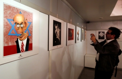 Um homem tira foto da exposi&ccedil;&atilde;o de caricaturas anti-israelenses, em Teer&atilde;, no dia 14 de maio de 2016