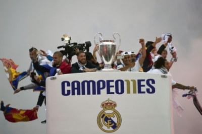 Real Madrid players hold up the trophy from the bus as they celebrate the team's win arriving on Plaza Cibeles in Madrid on May 29, 2016 after the UEFA Champions League final foobtall match between Real Madrid CF, Club Atletico de Madrid held in Milan, Italy.