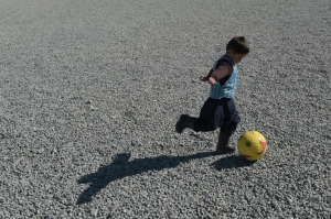 O menino Murtaza Ahmadi joga futebol com a camisa de pl&aacute;stico