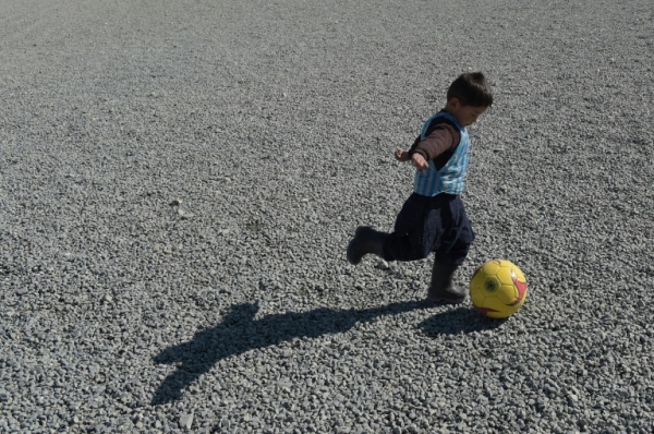 O menino Murtaza Ahmadi joga futebol com a camisa de pl&aacute;stico