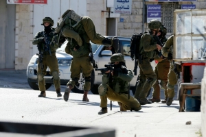 Soldado israelense carrega um colega ferido em confrontos com palestinos no campo de refugiados de Al-Amari