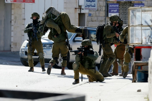 Soldado israelense carrega um colega ferido em confrontos com palestinos no campo de refugiados de Al-Amari