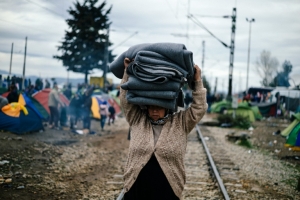 Mulher carrega cobertores em um acampamento improvisado perto do vilarejo grego de Idomeni, fronteira com a Maced&ocirc;nia