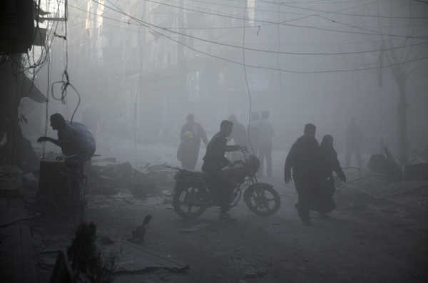 Pessoas caminham estre os destro&ccedil;os ap&oacute;s suposto ataque russo, em Douma, S&iacute;ria, no dia 7 de novembro de 2015