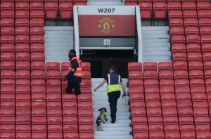 Um c&atilde;o farejador e membros dos servi&ccedil;os de seguran&ccedil;a fazem buscas na arquibancada do est&aacute;dio Old Trafford, em Manchester, no dia 15 de maio de 2016